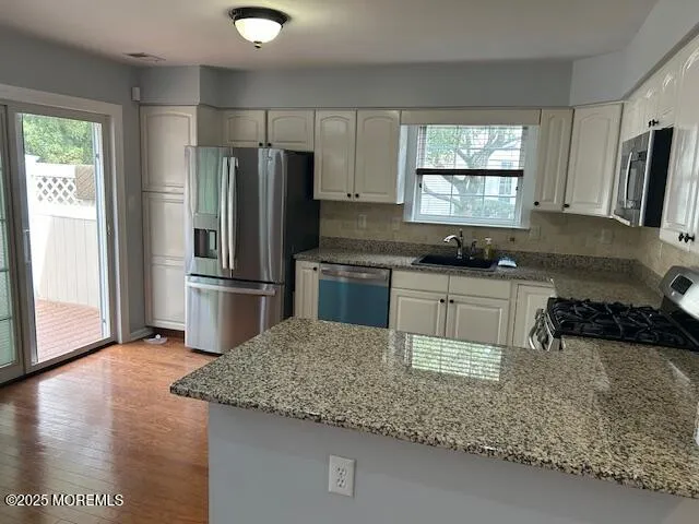a kitchen with kitchen island granite countertop a sink appliances and cabinets