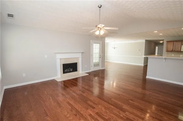 a view of an empty room with wooden floor and a fireplace