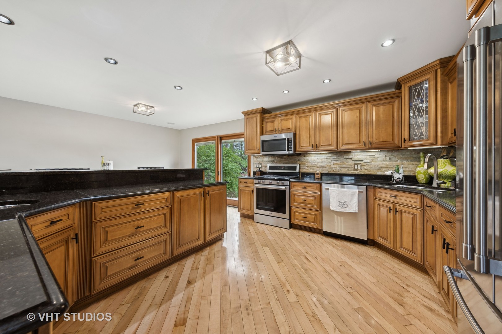8521 Una Avenue Naperville, IL 60565 - Photo 12 of 41 a kitchen with granite countertop wooden floors stainless steel appliances a sink and a window