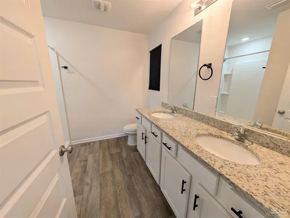 a bathroom with a granite countertop double vanity sink and mirror