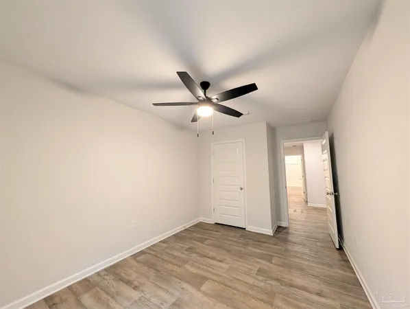 an empty room with wooden floor and ceiling fan