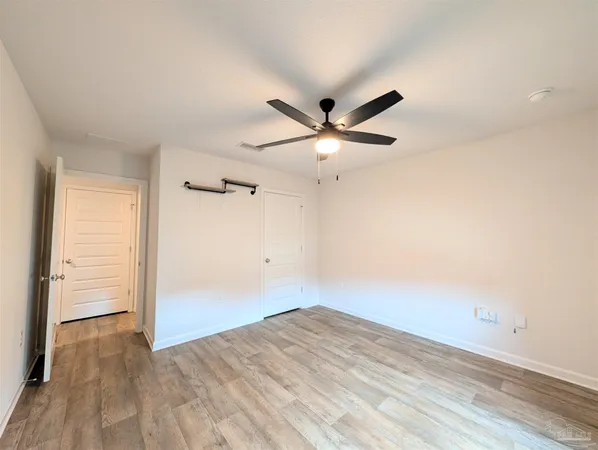 an empty room with closet and a ceiling fan
