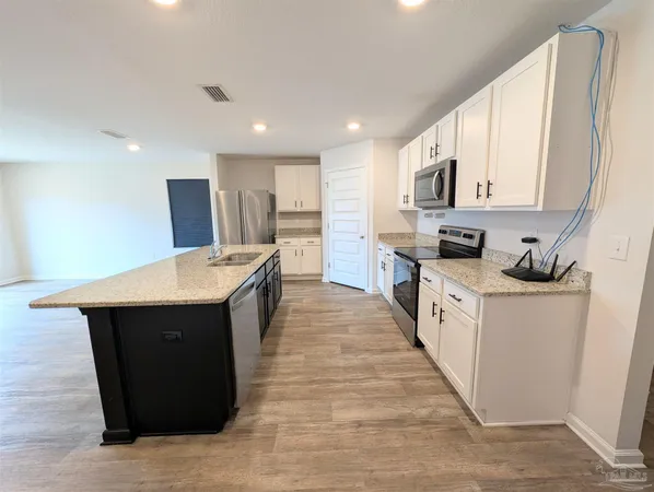 a kitchen with kitchen island granite countertop wooden cabinets a sink and a stove