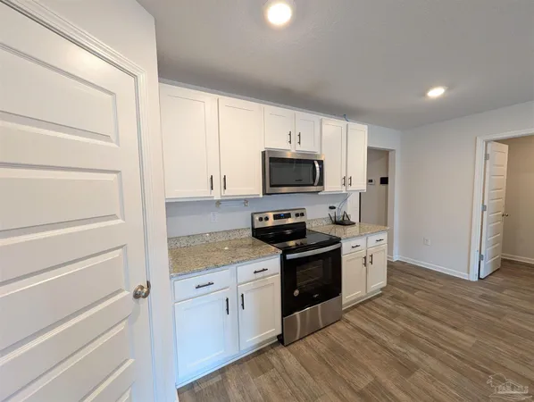 a kitchen with granite countertop white cabinets and stainless steel appliances