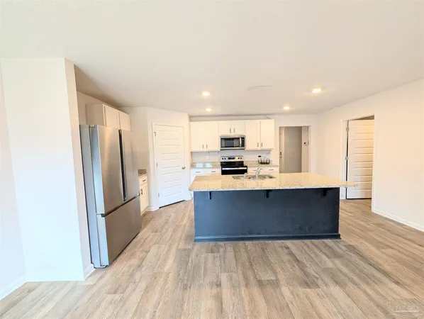 a view of kitchen with stainless steel appliances kitchen island granite countertop wooden floor
