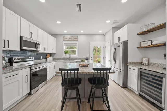 a kitchen with stainless steel appliances granite countertop a stove a sink dishwasher a refrigerator with a dining table and chairs