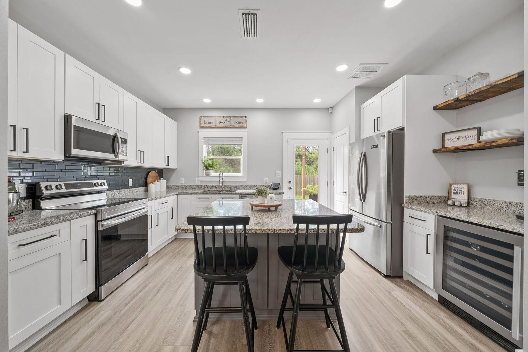 297 Cox Road Santa Rosa Beach, FL 32459 - Photo 11 of 41 a kitchen with stainless steel appliances granite countertop a stove a sink dishwasher a refrigerator with a dining table and chairs