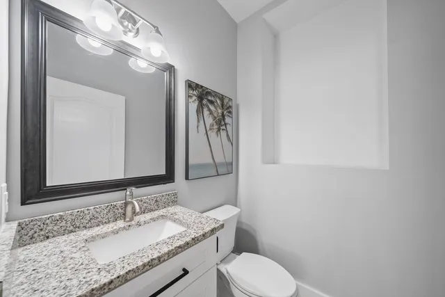 a bathroom with a granite countertop sink mirror vanity and toilet
