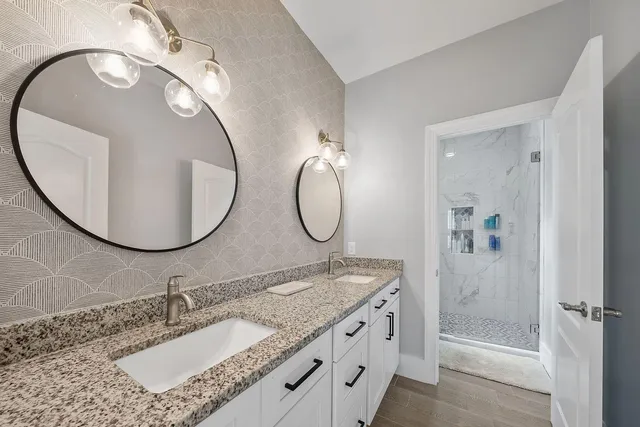 a bathroom with a granite countertop double vanity sink and a mirror