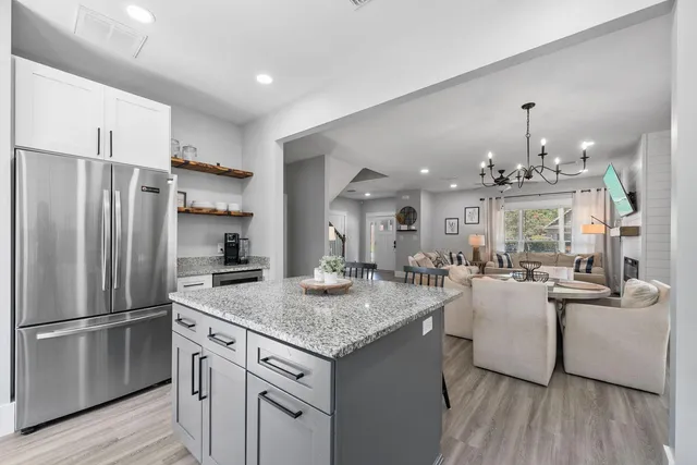 a kitchen with refrigerator and wooden floor