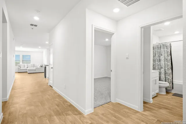 a view of a hallway with wooden floor and a living room