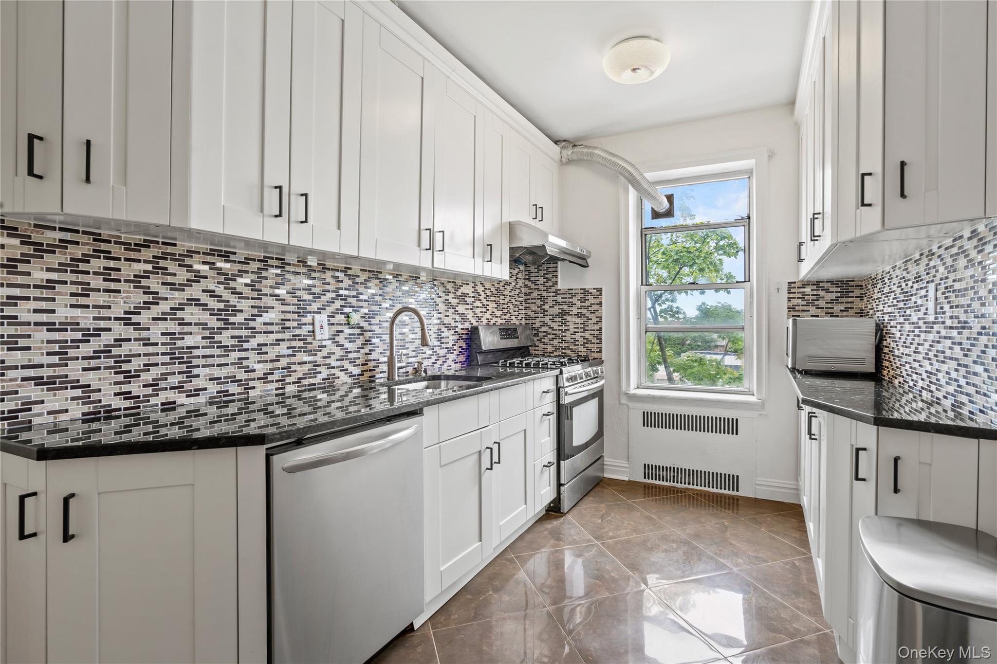 111-39 76th Road, Unit E7 Queens, NY 11375 - Photo 9 of 23 a kitchen with granite countertop white cabinets and window