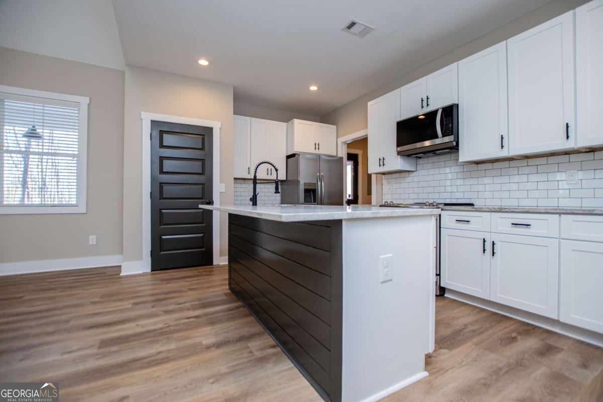 1605 5 Points Road Waco, GA 30182 - Photo 12 of 61 a kitchen with stainless steel appliances kitchen island granite countertop a stove top oven a sink and dishwasher with wooden floor