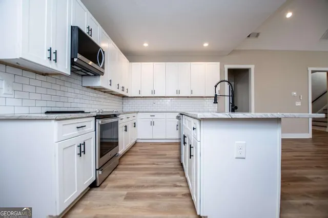 a kitchen with stainless steel appliances granite countertop a sink stove microwave and cabinets