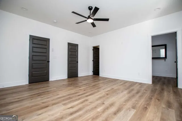 a view of empty room with wooden floor and fan