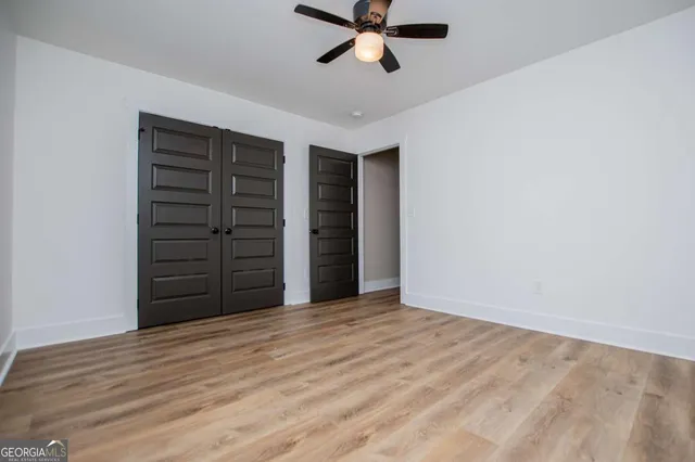 an empty room with closet and a ceiling fan