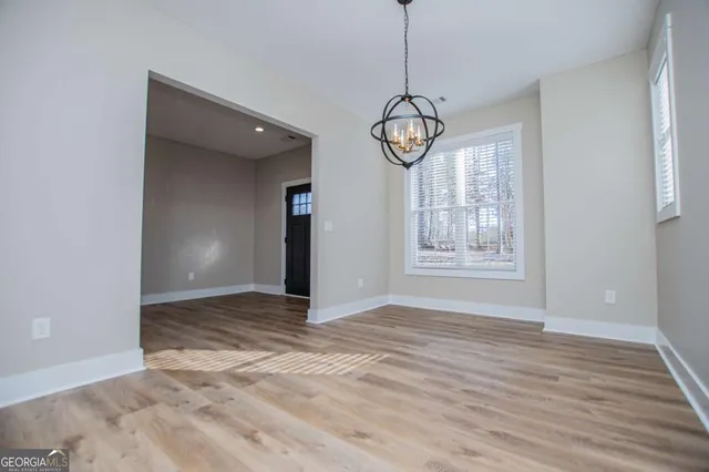 a view of an empty room with window and wooden floor