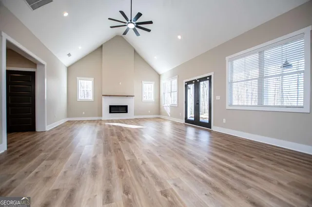 a view of an empty room with wooden floor fireplace and a window