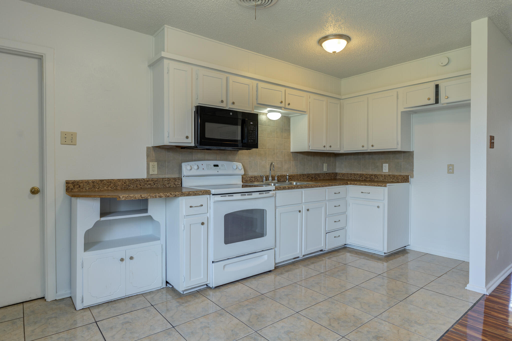 1313 Adrian Street Lubbock, TX 79403 - Photo 11 of 26 a kitchen with white cabinets and white appliances