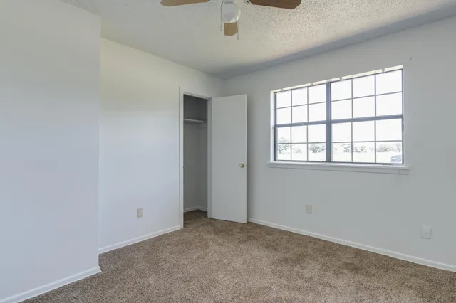 an empty room with windows and fan