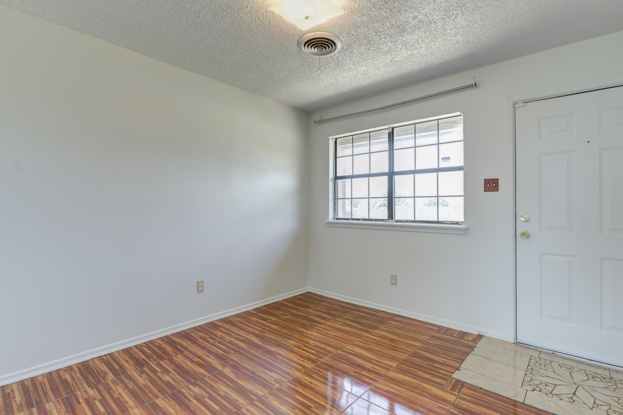 1313 Adrian Street Lubbock, TX 79403 - Photo 5 of 26 an empty room with wooden floor and windows