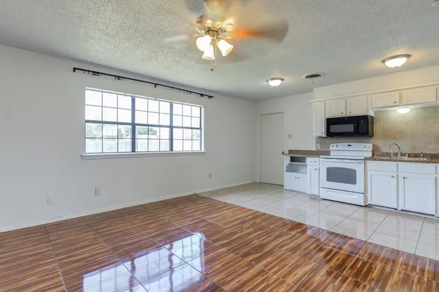 a kitchen with granite countertop a stove a sink and a microwave