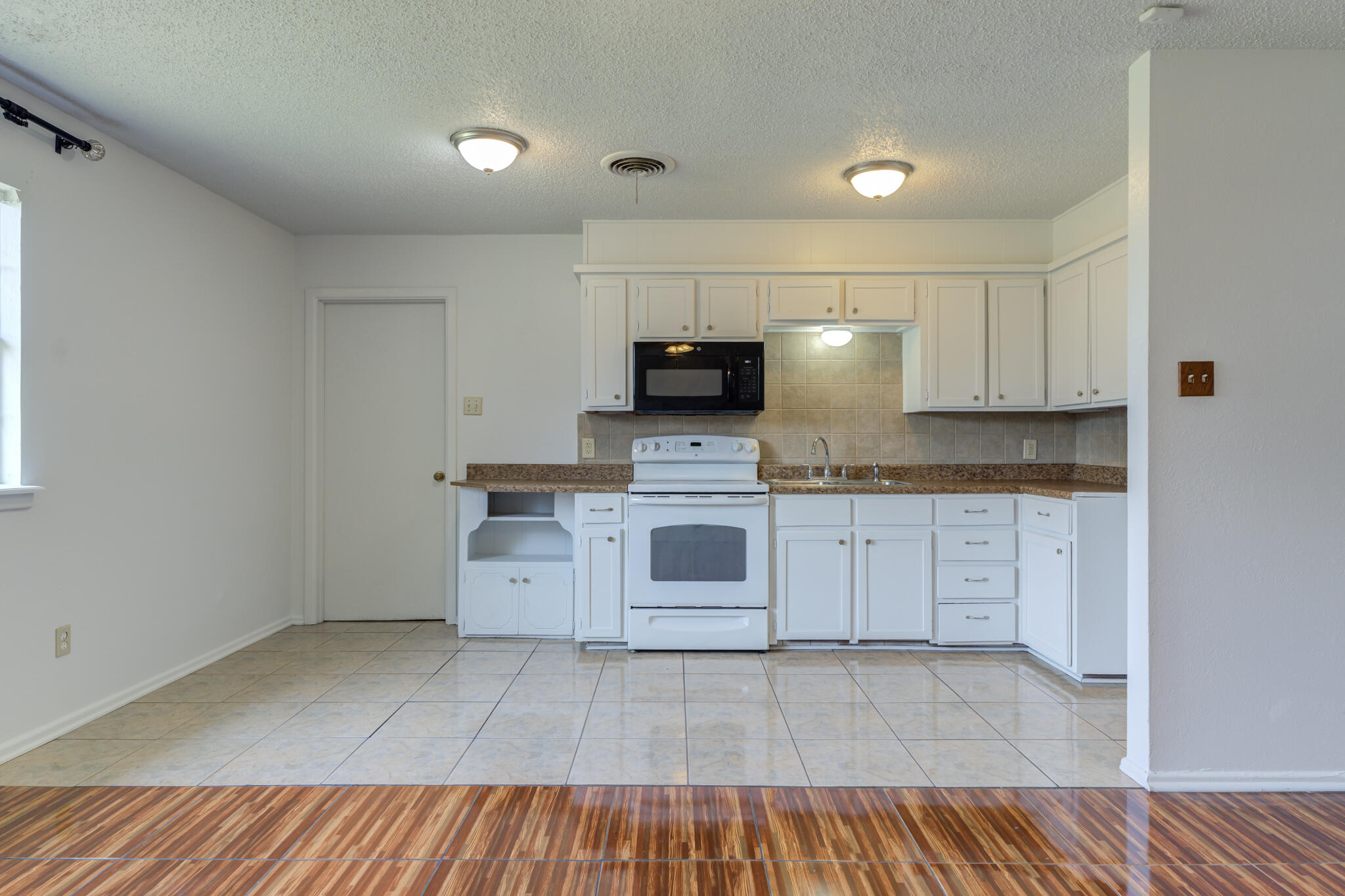1313 Adrian Street Lubbock, TX 79403 - Photo 9 of 26 a kitchen with a refrigerator and white cabinets
