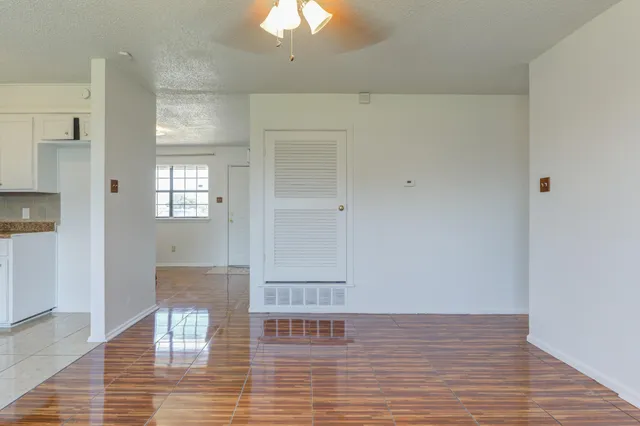 a view of empty room with wooden floor and fan