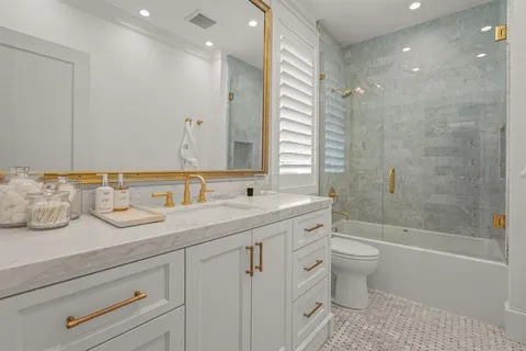 a bathroom with a granite countertop sink a toilet and a bathtub
