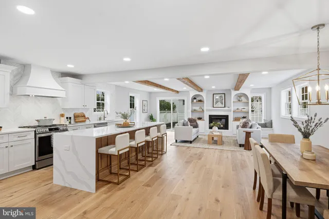 a large white kitchen with lots of counter space a sink appliances and dining table