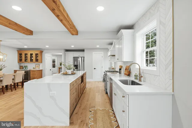 a large white kitchen with stainless steel appliances a sink and cabinets