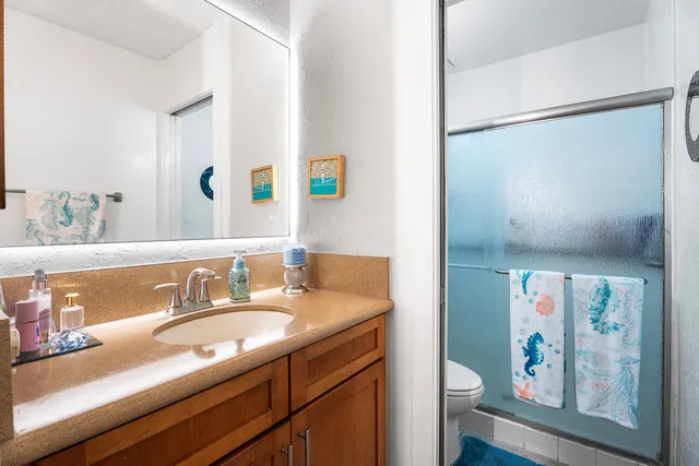 a bathroom with a granite countertop sink mirror vanity and toilet