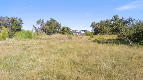 a view of a road with a yard and trees in the background