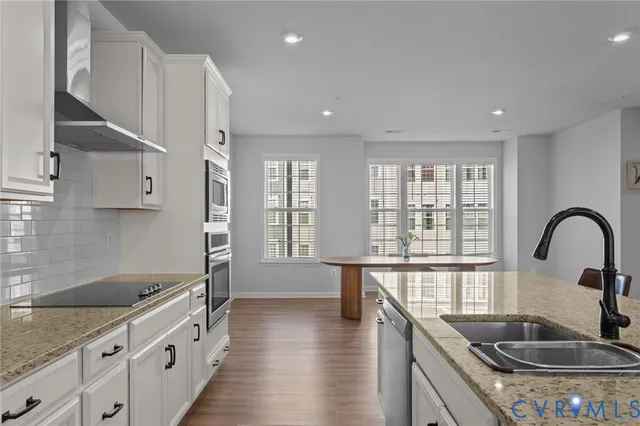 a kitchen with granite countertop a sink a counter space and stainless steel appliances