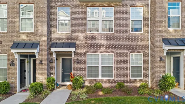 a front view of a brick house many windows and plants