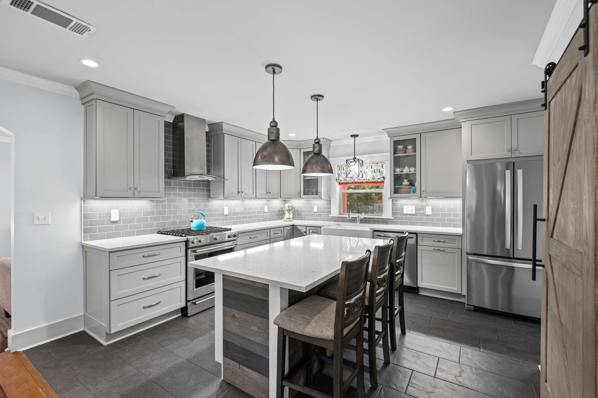 5079 Walnut Grove Road Memphis, TN 38117 - Photo 17 of 40 Modern kitchen featuring grey cabinetry, stainless steel appliances, a center island with pendant lighting, a tile backsplash, and dark tile flooring