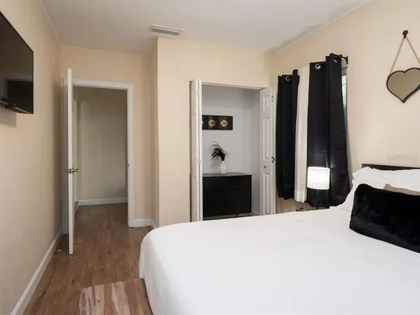 a bedroom with a bed and a flat tv screen on the dresser