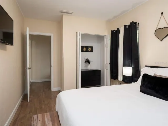 a bedroom with a bed and a flat tv screen on the dresser