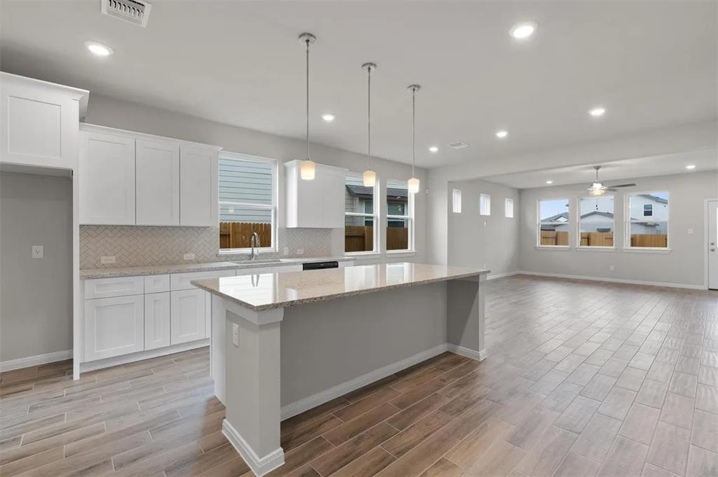 332 Stellar Wind Drive Georgetown, TX 78628 - Photo 11 of 29 A gleaming island with pendant lighting anchors this airy, open-concept kitchen and living area.