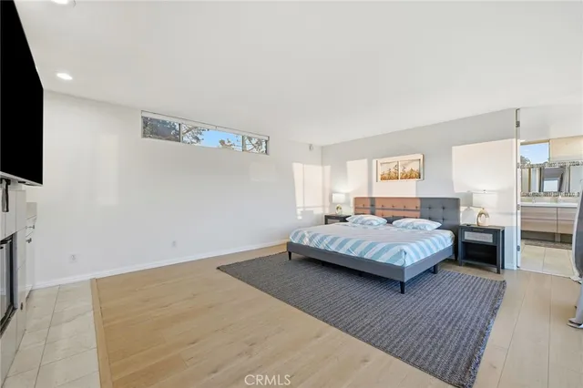 a bedroom with a bed wooden floor and a television