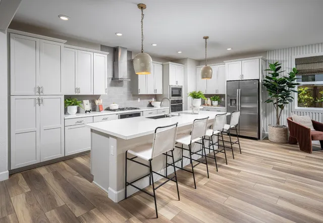 a kitchen with stainless steel appliances kitchen island a table chairs refrigerator microwave and cabinets