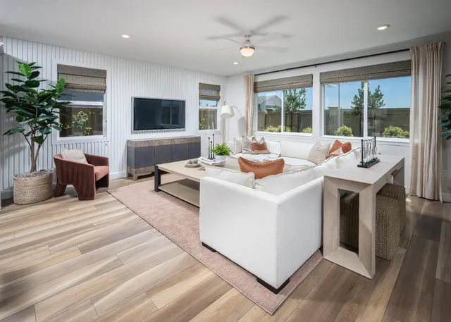 a living room with furniture a flat screen tv and a large window