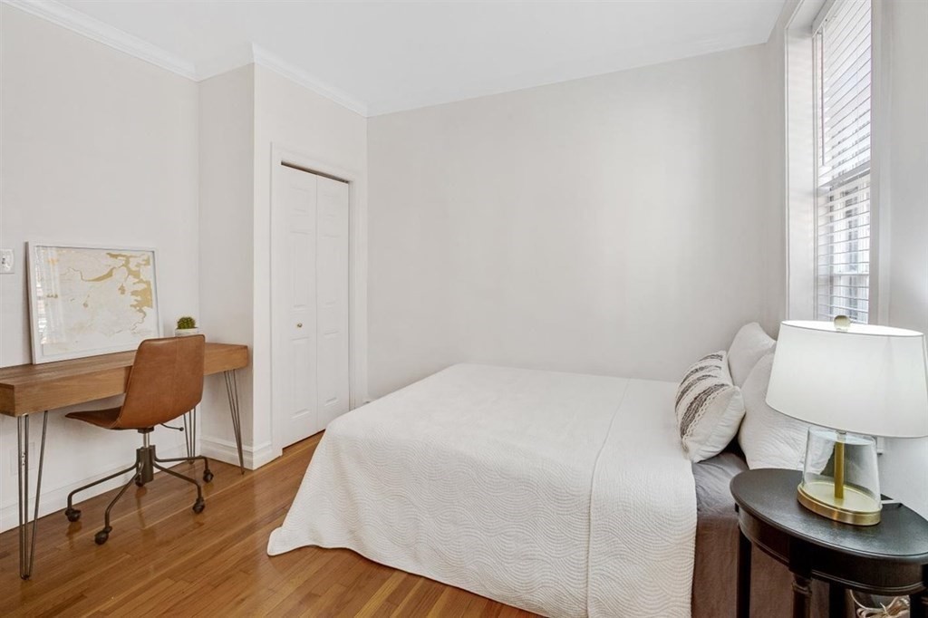 60 Myrtle Street, Unit 1 Boston, MA 02114 - Photo 6 of 14 a bedroom with a bed a chair and a potted plant with wooden floor