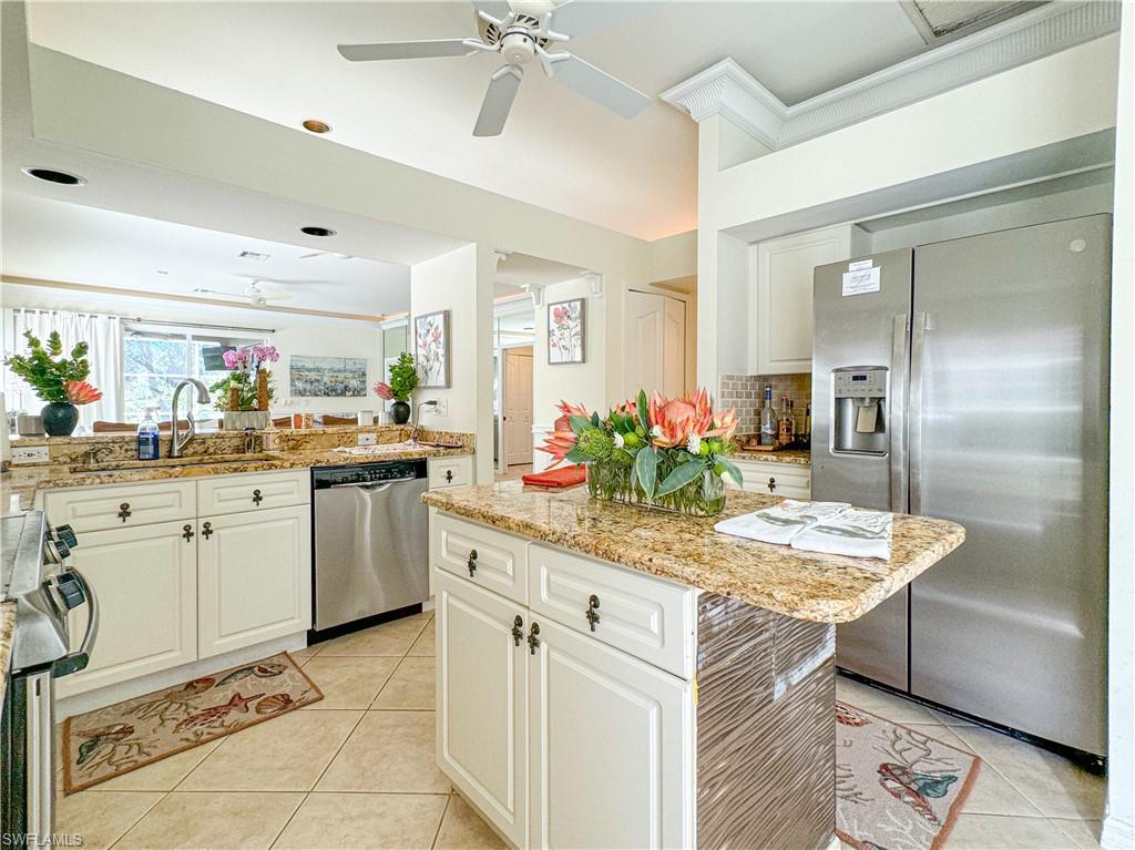 152 Napa Ridge Way Naples, FL 34119 - Photo 40 of 50 a kitchen with stainless steel appliances kitchen island granite countertop a table chairs sink and cabinets