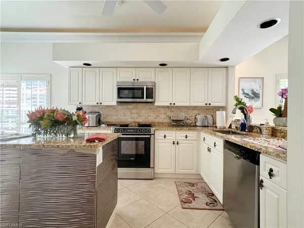 a kitchen with granite countertop a sink counter top space appliances and cabinets