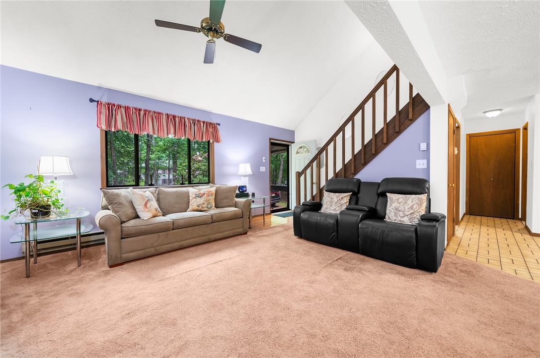 222 Powder Horn Road Henryville, PA 18332 - Photo 4 of 25 A vaulted ceiling living area with a ceiling fan, plush carpeting, and a grand staircase.