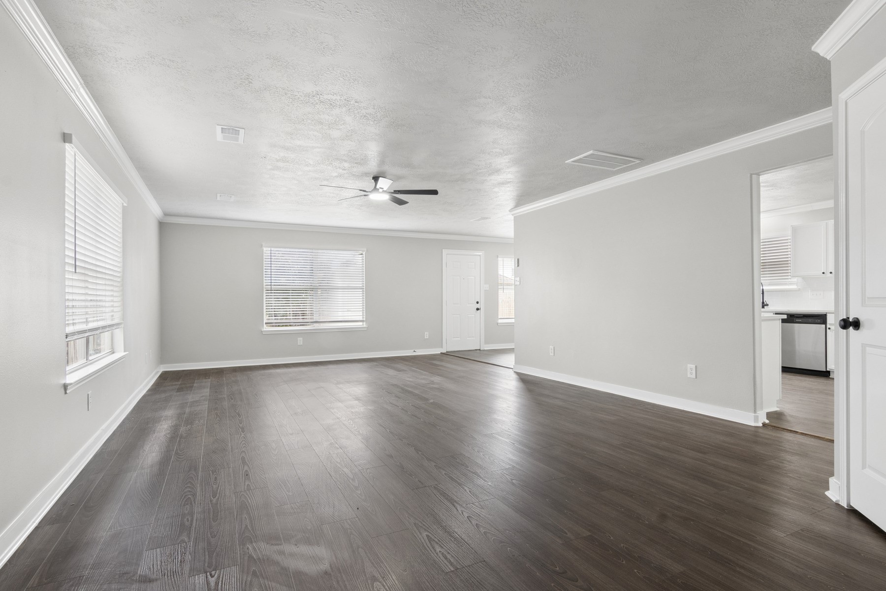 14211 Brunswick Point Lane Houston, TX 77047 - Photo 6 of 17 Spacious, bright living area with large windows, hardwood floors, and neutral walls. Features a ceiling fan and convenient access to the kitchen.