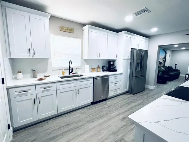 a kitchen with refrigerator and white cabinets