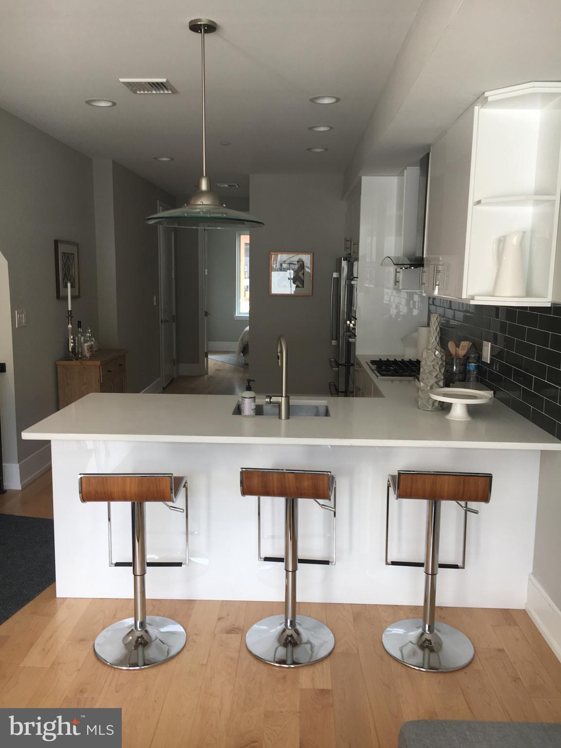 1008 South 17th Street, Unit A Philadelphia, PA 19146 - Photo 1 of 13 a kitchen with center island stainless steel appliances and living room view