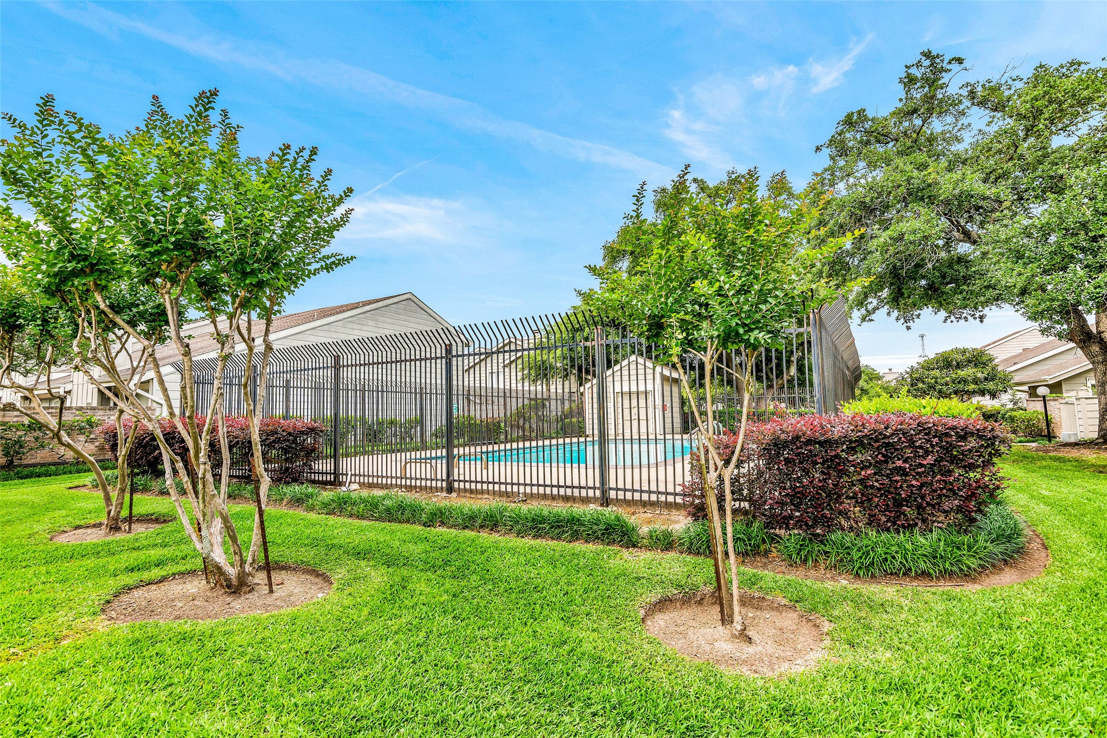 13009 Wirevine Lane Houston, TX 77072 - Photo 18 of 18 Well-maintained, fenced community pool surrounded by lush landscaping and mature trees, providing a serene and inviting outdoor space.